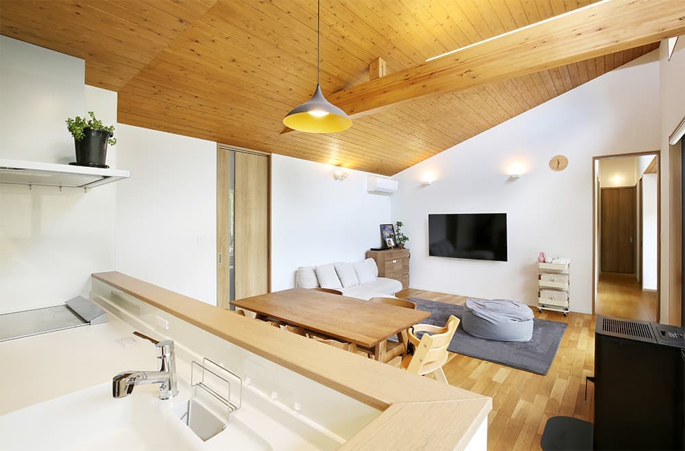 緑に開いた「くの字」の平屋の家